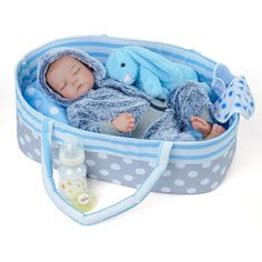 a baby doll laying in a blue and white polka dot basket with a stuffed animal