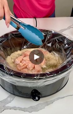 someone is cooking in an electric pressure cooker with plastic wrap around the lid and spoon