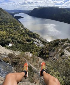 someone is sitting on top of a mountain overlooking a lake