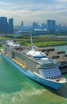 a large cruise ship in the water next to a dock with buildings and skyscrapers behind it