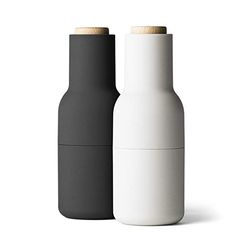 two black and white bottles sitting next to each other on a white surface, one with a wooden top