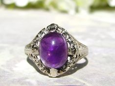 Antique Edwardian engagement ring with an amethyst cabochon that would make a beautiful alternative engagement or promise ring for someone looking for that "something different!" Gemstones were a very popular choice used in Victorian and Edwardian engagement rings and young couples today are using them again for a unique betrothal ring! The natural amethyst cabochon measures approximately 9 x 7mm which is about a 1.86 carat stone. It is held in place with four prongs and the 14K white gold setti Antique Amethyst Ring, Amethyst Art, Filigree Wedding Ring, Purple Magic, Accessories Guide, February Birthstone Ring, Edwardian Engagement Ring, Beautiful Rings Vintage, Alternative Wedding Rings