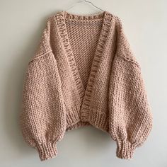 a pink sweater hanging on a white wall