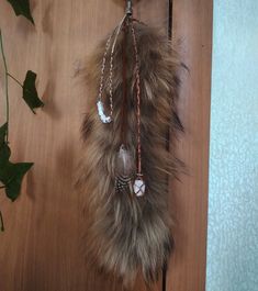 a brown and white feather hanging from a hook on a wooden floor next to a plant