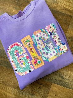 a purple t - shirt with the word love spelled out in colorful letters on it