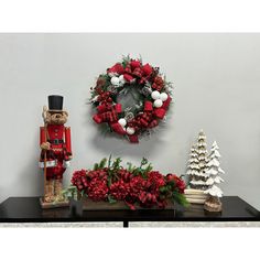 a nutcracker is standing next to a wreath and christmas decorations on a table