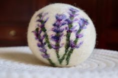 a white ball with purple and green flowers on it sitting on top of a table