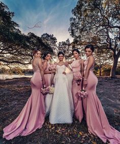 the bride and her bridesmaids pose for a photo in front of some trees