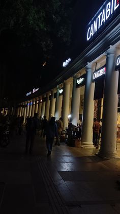 people are walking around in front of a store at night