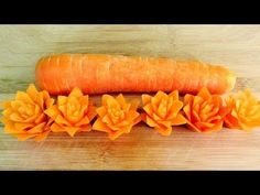 an orange carrot sitting on top of a wooden cutting board next to flowers and leaves