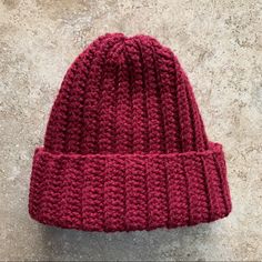 a red knitted hat sitting on top of a cement floor