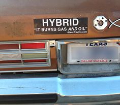 the back end of a car with a bumper sticker that reads hybrid it burns gas and oil