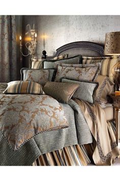 a large bed covered in lots of pillows next to a night stand with two lamps on it