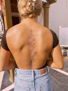 a woman with a flower tattoo on her back is standing in front of a building