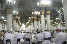 a group of men sitting around each other in a room with columns and lights on the ceiling