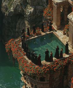 a group of people standing around a pool surrounded by flowers