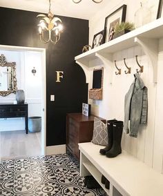 the entryway is decorated with black and white tiles, coat racks, and boots