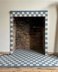 an empty fireplace with blue and white tiles on the floor