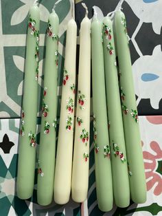 four green candles with white frosting and red berries on them sitting next to each other