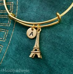 "This listing is for an Eiffel tower bangle bracelet. This bracelet is adjustable, which makes it a great gift for someone if you don't know their wrist size. Just squeeze to adjust! :) One size fits most. You'll be able to choose your initial from the drop-down menu, and you can also choose to have these charms placed on a keychain or necklace instead. **Please see the second photo for charm scale. These are SMALL charms. The initial charm measures 3/8\". If you want a different quantity than you see listed here, just write and ask!  **Please note that this is gold-tone and not actually made from real gold. ITEM CARE: We recommend our items never come into contact with moisture, for best results. - - - - - - - Sign up for our newsletter to receive coupons and updates on new items! Follow Adjustable Chain Bangle As A Gift, Adjustable Metal Charm Bracelet, Adjustable Metal Name Bracelet For Gift, Adjustable Charms Bangle, Gold Cuff Bracelet For Bridesmaid Gift, Charm Bracelet For Bridesmaid Gift, Personalized Metal Cuff Bracelet, Adjustable Gold Bracelets For Bridesmaids, Adjustable Charms Bangle For Gift