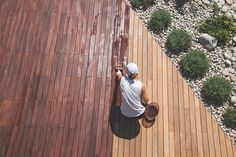 a person standing on top of a wooden deck next to a green bush and rocks