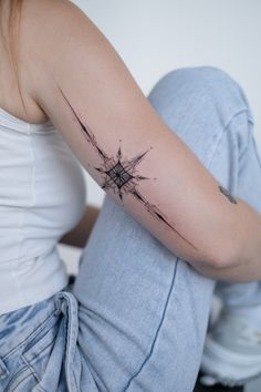 a woman sitting on the floor with her arm wrapped in barbed wire and tattooing it