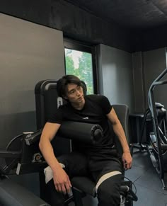 a man sitting on top of a bench next to a window in a gym room