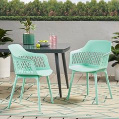 two chairs sitting at a table on top of a rug next to potted plants