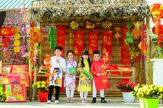 three children are standing in front of an outdoor shrine decorated with red and yellow decorations