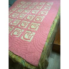 a pink quilted bed spread on top of a wooden table