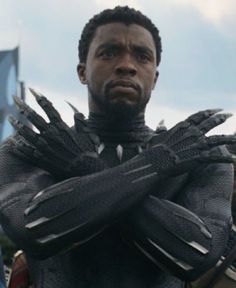 the black panther is standing in front of other people with his hands on his chest