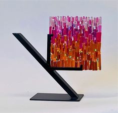 a multicolored glass sculpture on a metal stand