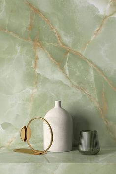 a white vase sitting on top of a counter next to a wall mounted clock and other items