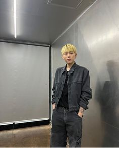 a young man standing in front of a metal wall with his hands in his pockets