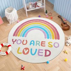 a rainbow rug that says you are so loved on the floor next to other toys