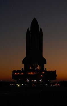 the space shuttle is lit up at night with lights on it's back end