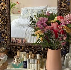 a vase filled with flowers sitting on top of a table next to a mirror and other items