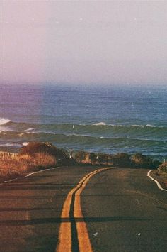 an empty road with the ocean in the background