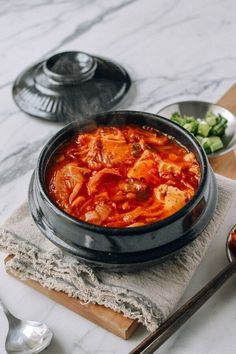 a bowl of food sitting on top of a table next to other bowls and spoons