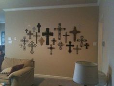 a living room filled with furniture and lots of crosses hanging on the wall above it