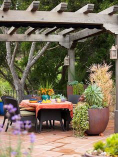 an outdoor dining area with potted plants on the patio table and chairs around it