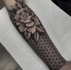 a black and white flower of life tattoo on the arm with geometrical patterning