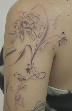 the back of a woman's shoulder with flowers and butterflies on her left arm