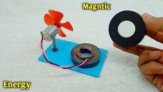 a hand holding a magnet and an electric wheel on top of a piece of paper