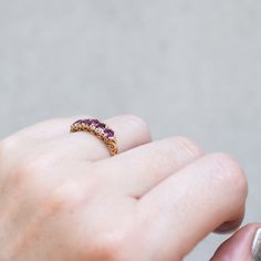 Cool magenta rubies are set in swirling filigree in this antique gold ring. The cushion shape of the stones pop from the carved band and tiny diamonds bookend each end. Originating from England in 1890, this bold ring is one of a kind. Stones: Five Rubies, Total 1.50tcw, Small White DiamondsMetal: 18k Yellow GoldMeasurements: Setting length: 13.7mm, Setting width: 5.1mm, Setting height: 4.3mm, Band width: 2.3-1.8mmWeight: 3g Size 6.5 in stock Shipping and Delivery: IN STOCK items will ship within 2 business days Sizes not In Stock will be Resized Resize Fee may apply Please allow 2 weeks for delivery All Resize items are final sale Please make sure to have your correct ring size before ordering Prices may vary by variant Antique Gold Ring, Antique Gold Rings, Deep Magenta, Bold Rings, Tiny Diamond, Antique Vintage Jewelry, 18k Yellow Gold Ring, Yellow Gold Ring, Hoop Ring