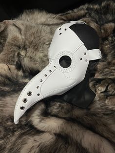 a white mask with holes on it sitting on a fur covered surface