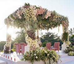 an outdoor wedding setup with pink chairs and flowers