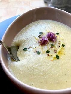 a white bowl filled with soup and garnished with flowers