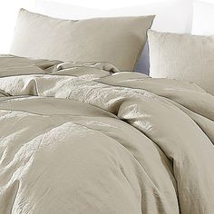 an unmade bed with beige sheets and pillows