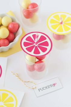 some candies are sitting in small cups with lemons and candy on the table